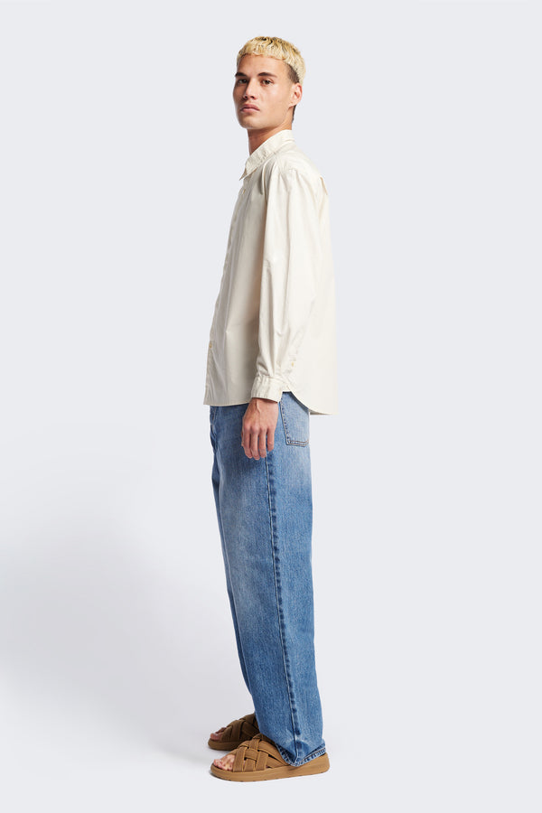 Side of the Iberia Long Sleeve Shirt in Ecru, featuring a built-in collar, semi-concealed placket, and a curved hem. Available in XS, S, M, L, XL