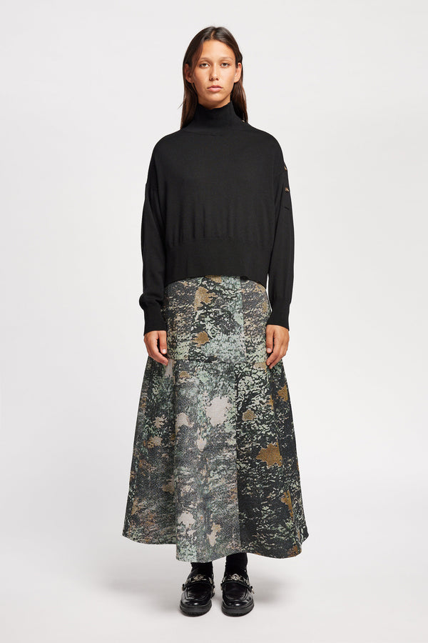 Front view of Model wearing merino wool mock neck sweater with shoulder button detail in black.