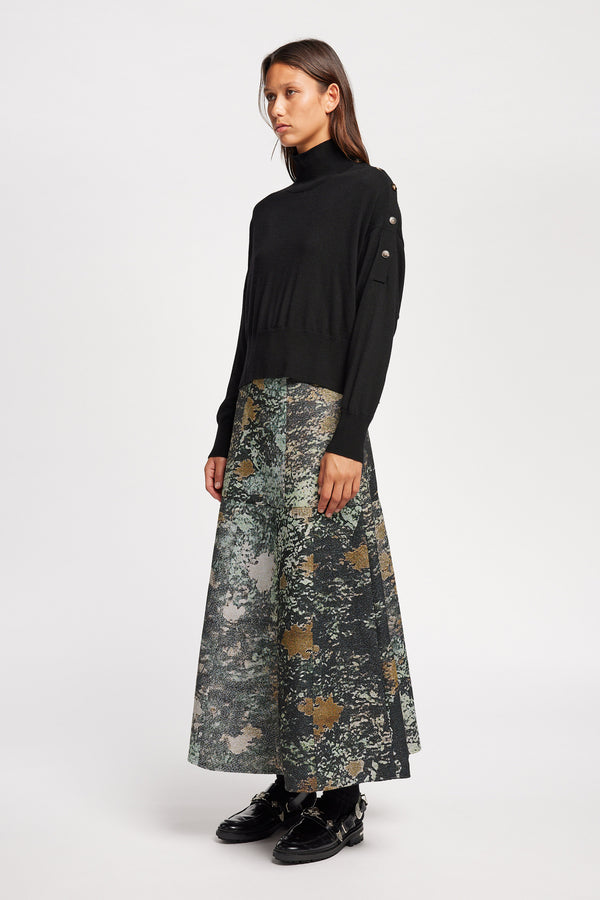 Front angle view of Model wearing merino wool mock neck sweater with shoulder button detail in black.
