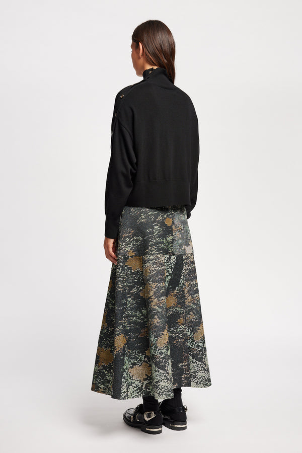 Back view of Model wearing merino wool mock neck sweater with shoulder button detail in black.