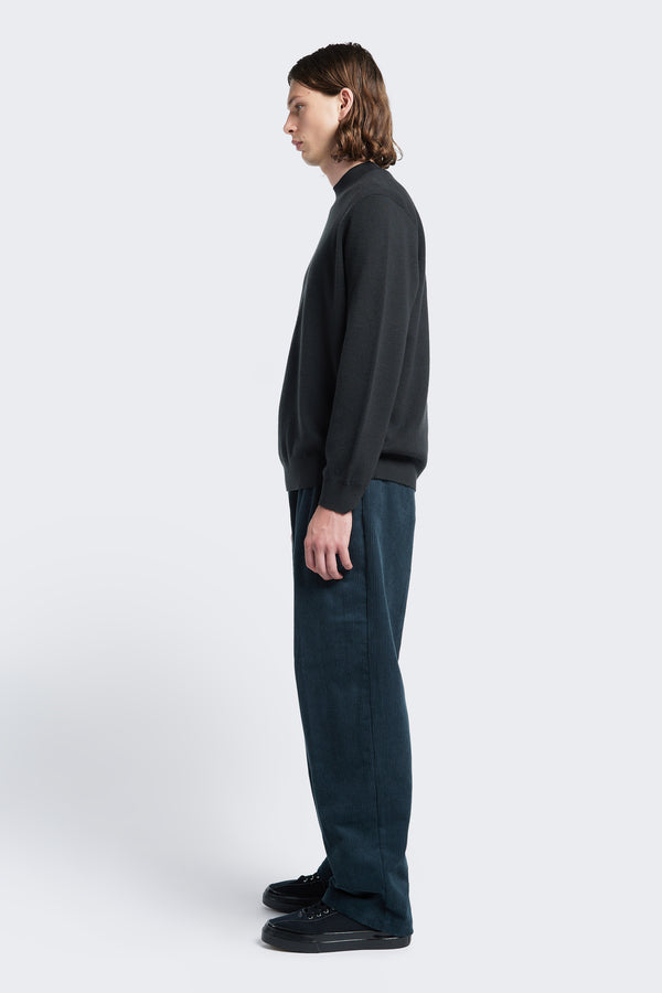 Side profile of the Dose Merino Sweater Charcoal, knitted in a fine Merino wool in a milano knit construction, this mock-neck style is finished with a 1x1 rib hemline and cuffs.