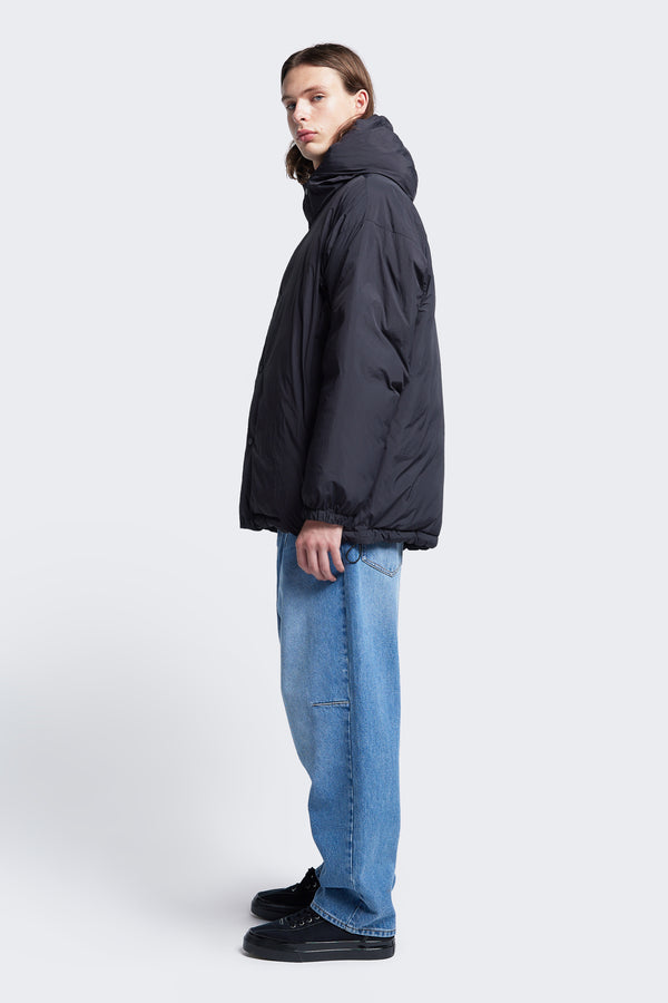 Side profile of the Majority Quilted Jacket Black. This puffer jacket is made with 100% post-consumer down fill and 100% recycled nylon. Available in five sizes.