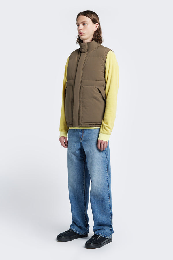 The Reset Quilted Vest Brown is made with 100% post-consumer down fill. This puffer vest has a high neckline, elasticated armholes for comfort and internal and side pockets with press-stud closure. Made to fit comfortably over knitwear, tees and more.
