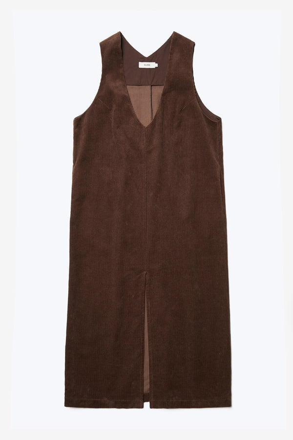 The front of the Arc Dress, a full length pinafore with a deep v-neck and centre-front spilt. Made from thick wale corduroy in Dark Brown.