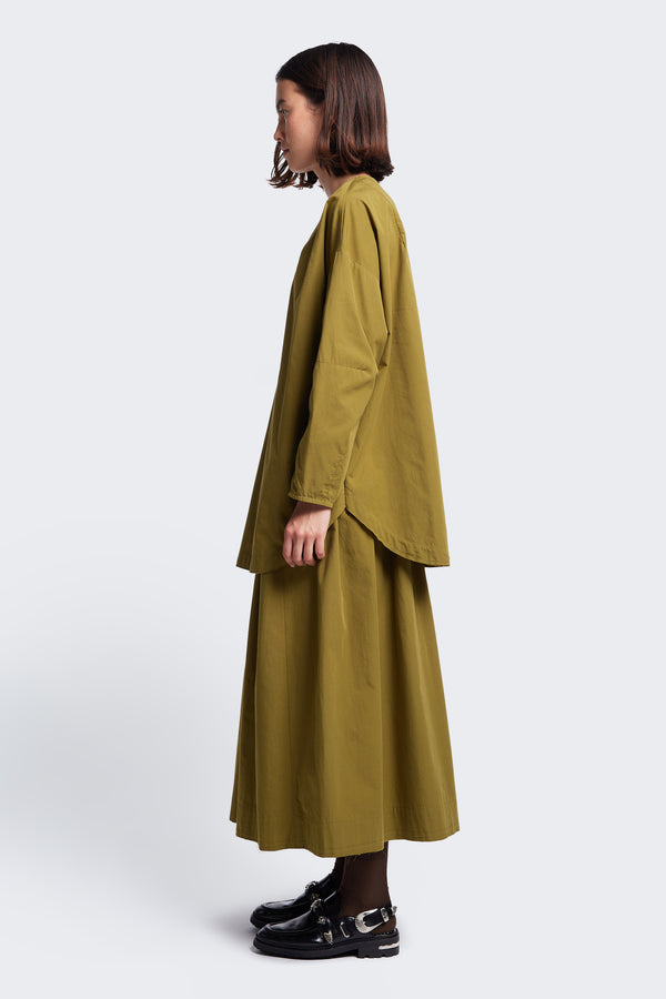Side profile of the Plateau Blouse Moss Green, a long sleeve shirt with a relaxed silhouette. This blouse has a rounded scoop hem.