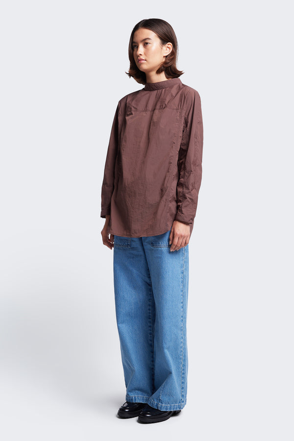 The Women's Waking Blouse Cocoa Brown is a relaxed style with front panel stitch detail. Featuring a stand collar with centre back button opening, dropped shoulders and a hem cuff with button opening. Made from 100% nylon.