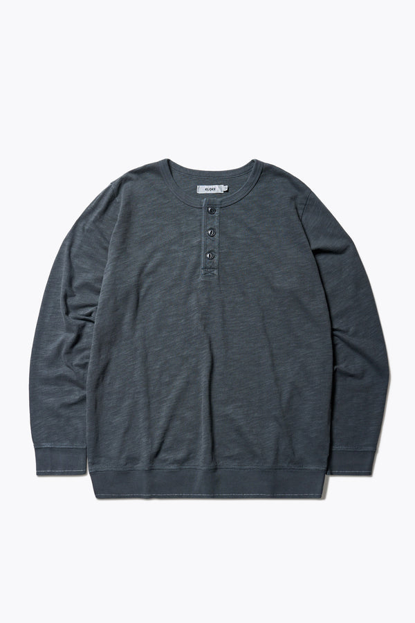 The Asperse Henley in Black, featuring a three-button placket, ribbed cuffs and hem, and a garment pigment-dyed finish. Available in 5 sizes.