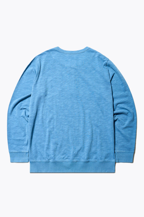 Back of The Asperse Henley in Blue, featuring a three-button placket, ribbed cuffs and hem, and a garment pigment-dyed finish. Available in 5 sizes.