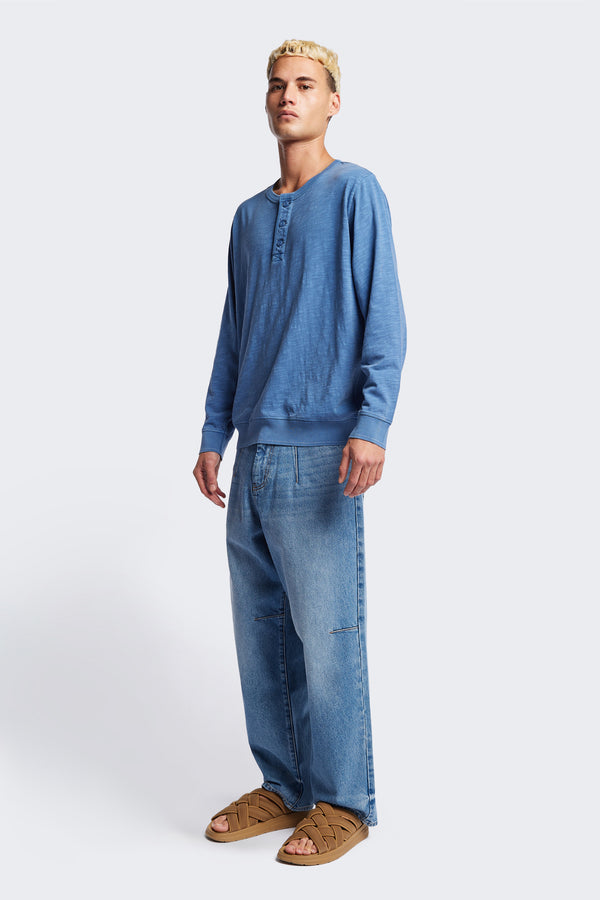 The Asperse Henley in Blue, featuring a three-button placket, ribbed cuffs and hem, and a garment pigment-dyed finish. Available in 5 sizes.