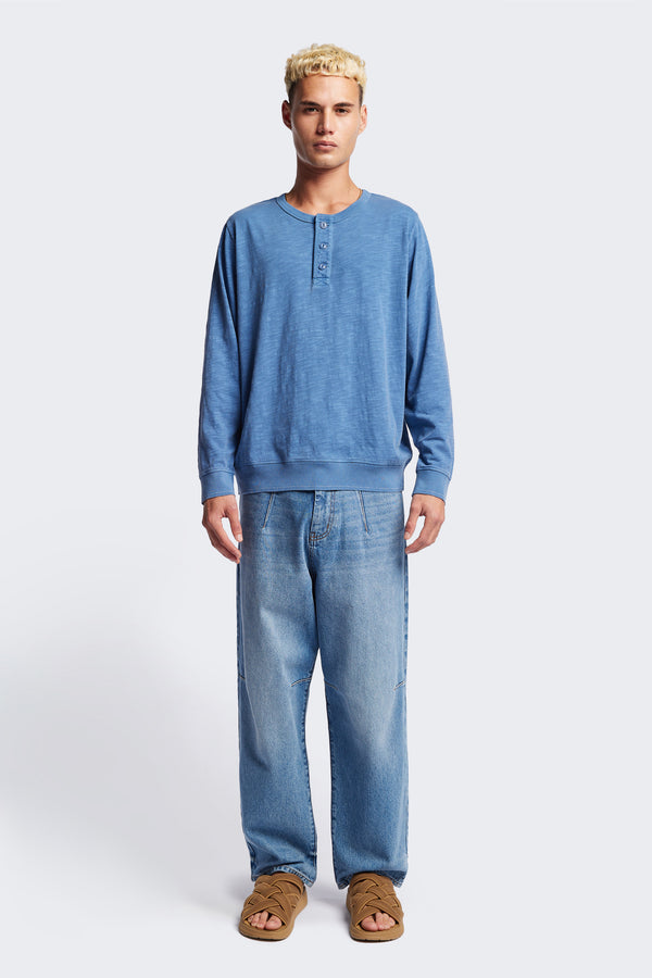 The Asperse Henley in Blue, featuring a three-button placket, ribbed cuffs and hem, and a garment pigment-dyed finish. Available in 5 sizes.
