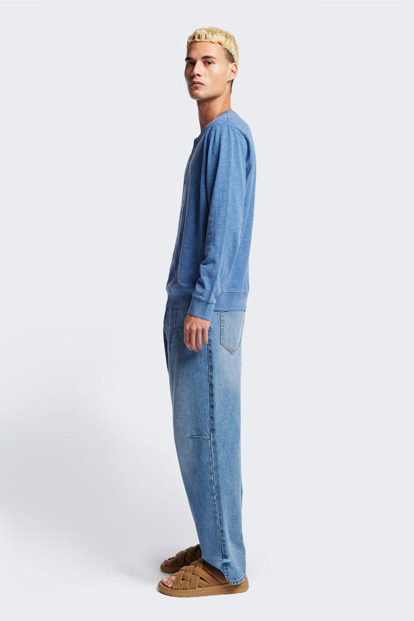 Side of The Asperse Henley in Blue, featuring a three-button placket, ribbed cuffs and hem, and a garment pigment-dyed finish. Available in 5 sizes.