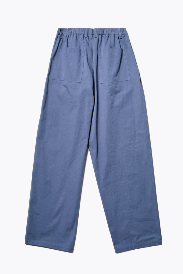 Back of The Boulder Pleat Pants in Blue, crafted from cotton herringbone twill, featuring side slant pockets, back patch pockets, and an elastic waistband with internal pull. Available in 5 sizes.