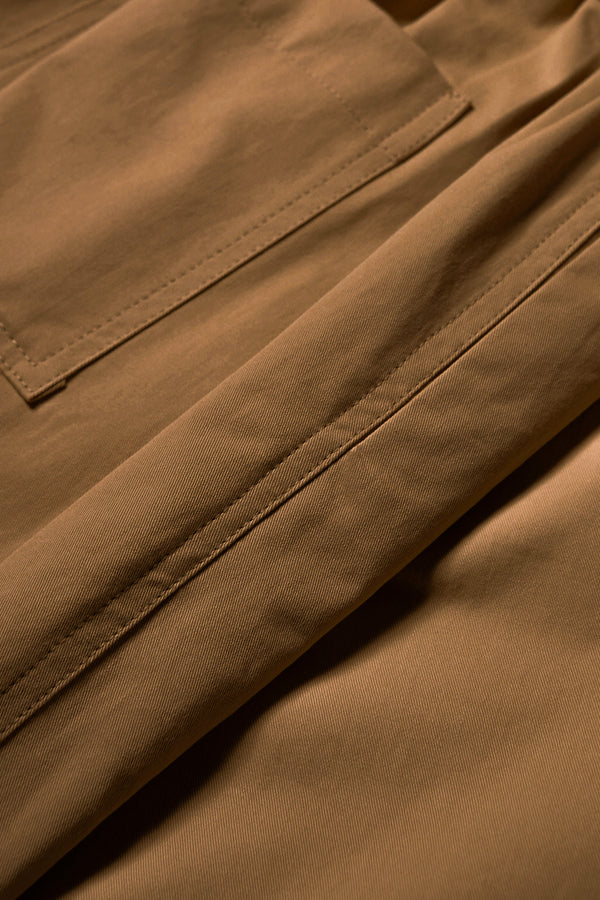 Close up fabric shot of The Boulder Pleat Pants in Brown, crafted from cotton herringbone twill, featuring side slant pockets, back patch pockets, and an elastic waistband with internal pull. Available in 5 sizes.