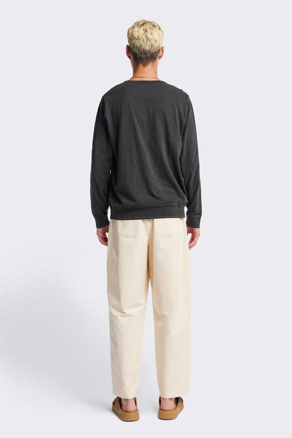Back of The Boulder Pleat Pants in Chalk Beige, crafted from cotton herringbone twill, featuring side slant pockets, back patch pockets, and an elastic waistband with internal pull. Available in 5 sizes.