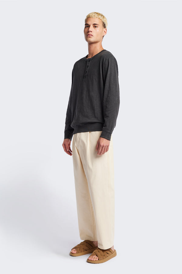 The Boulder Pleat Pants in Chalk Beige, crafted from cotton herringbone twill, featuring side slant pockets, back patch pockets, and an elastic waistband with internal pull. Available in 5 sizes.