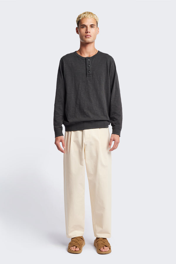 The Boulder Pleat Pants in Chalk Beige, crafted from cotton herringbone twill, featuring side slant pockets, back patch pockets, and an elastic waistband with internal pull. Available in 5 sizes.
