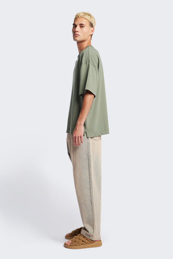 Side of the Fragment Pleat Denim Pant in Blue pink Fade, a relaxed fit and loose leg design, featuring an elasticated waistband, traditional denim front pockets, and patch back pockets. Available in 5 sizes.