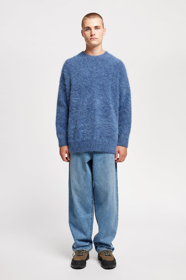 Front of Model wearing oversized fluffy knit crew neck sweater in indigo blue.