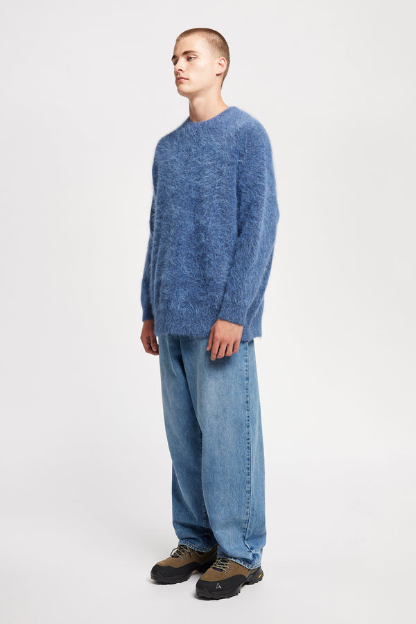 Front angle of Model wearing oversized fluffy knit crew neck sweater in indigo blue.