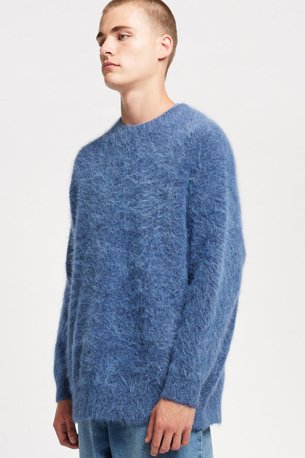 Front angle of Model wearing oversized fluffy knit crew neck sweater in indigo blue.