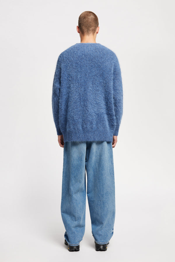 Back of Model wearing oversized fluffy knit crew neck sweater in indigo blue.