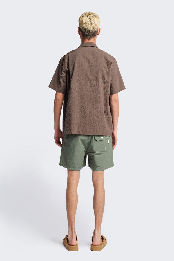 Back of the Mirari Shirt in Brown, a relaxed short-sleeve camp shirt in soft textured cotton seersucker with an open collar and laid-back fit, styled for versatile wear. Available in 5 sizes.