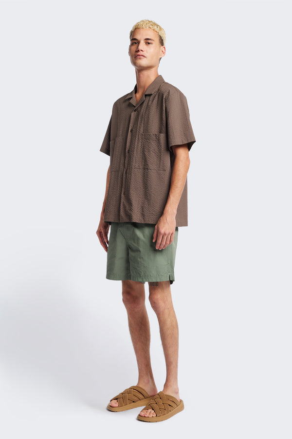 The Mirari Shirt in Brown, a relaxed short-sleeve camp shirt in soft textured cotton seersucker with an open collar and laid-back fit, styled for versatile wear. Available in 5 sizes.