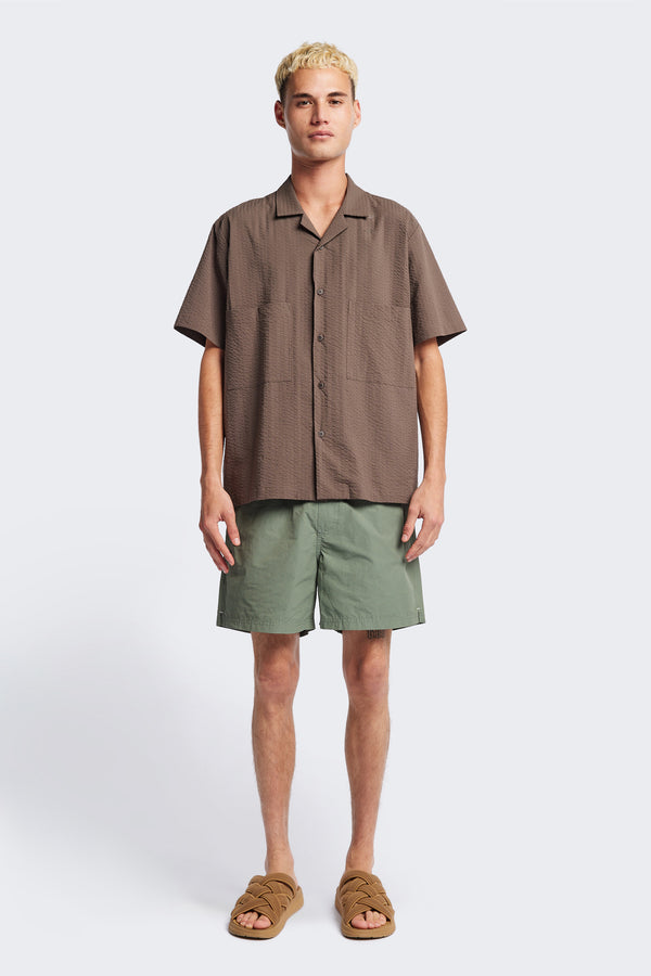The Mirari Shirt in Brown, a relaxed short-sleeve camp shirt in soft textured cotton seersucker with an open collar and laid-back fit, styled for versatile wear. Available in 5 sizes.