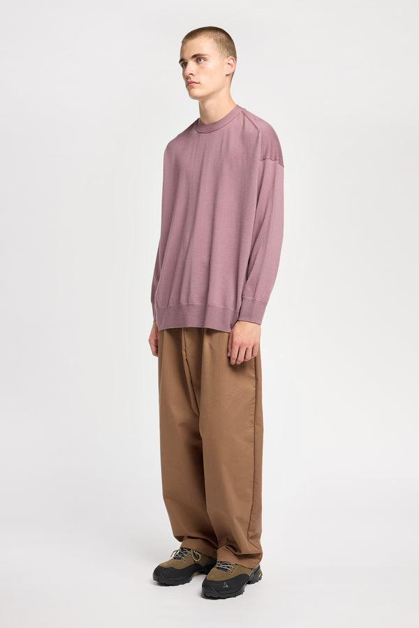 Front angle of Model wearing loose fit merino wool crew neck sweater with exposed seams in mauve.