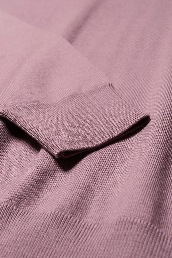 Close up fabric details of the Pitch loose fit merino wool crew neck sweater with exposed seams in mauve.