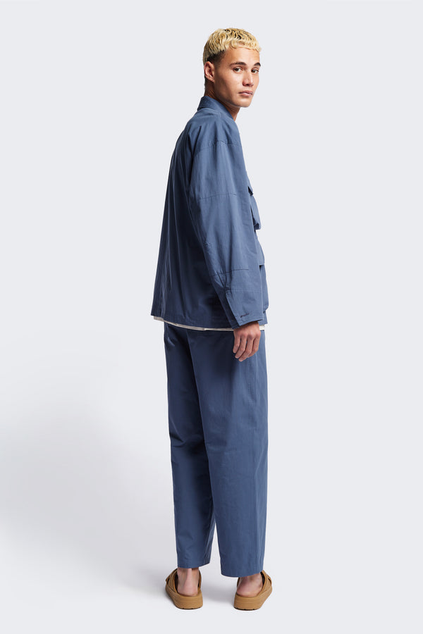 The Pressure Jacket in Blue, a relaxed boxy long sleeve jacket in washed cotton herringbone with 3D patch pockets and hidden zip openings. Available in 5 sizes.