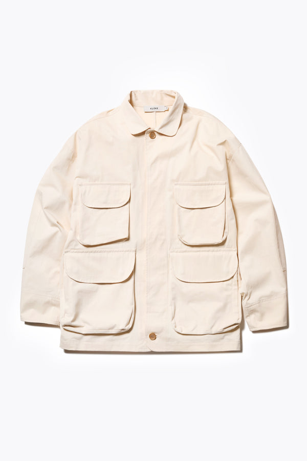 The Pressure Jacket in Chalk White, a relaxed boxy long sleeve jacket in washed cotton herringbone with 3D patch pockets and hidden zip openings. Available in 5 sizes.