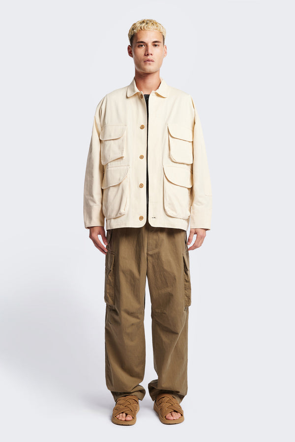 The Pressure Jacket in Chalk White, a relaxed boxy long sleeve jacket in washed cotton herringbone with 3D patch pockets and hidden zip openings. Available in 5 sizes.