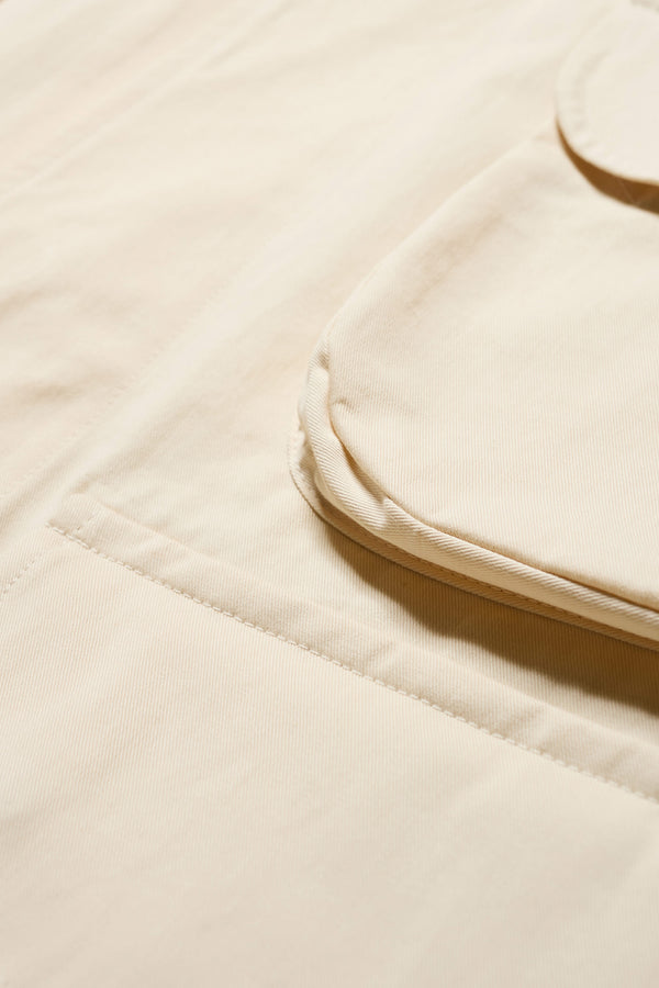 Close up details of The Pressure Jacket in Chalk White, a relaxed boxy long sleeve jacket in washed cotton herringbone with 3D patch pockets and hidden zip openings. Available in 5 sizes.