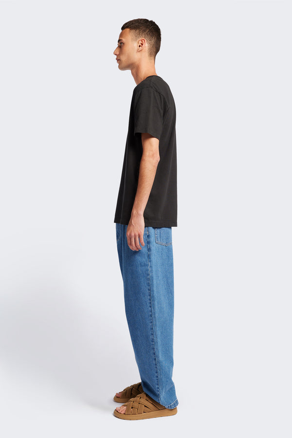 Side profile of The Stratus Henley T-shirt in Vintage Black. Garment-dyed in soft cotton jersey with three-button placket and coverstitched hems. Available in 5 sizes.