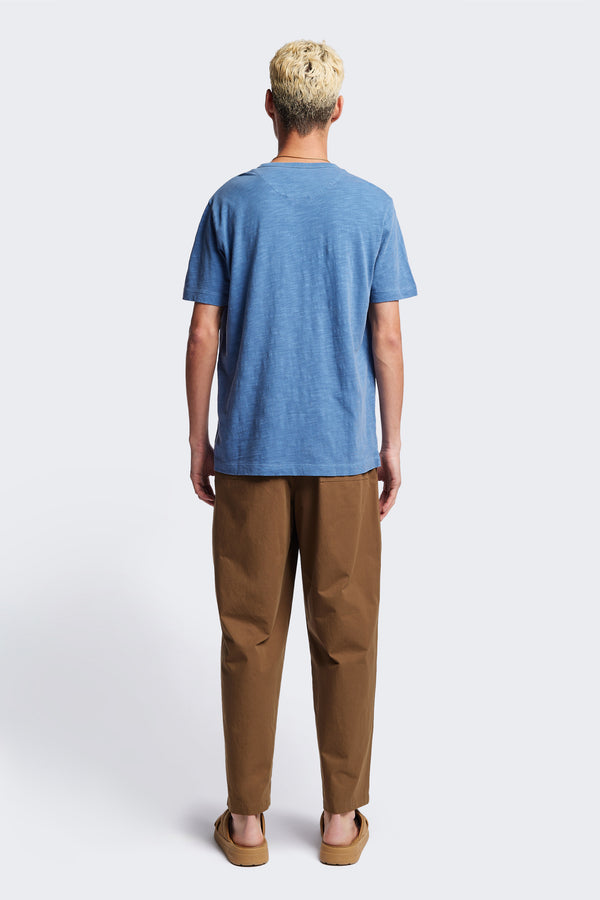 Back of The Stratus Henley T-shirt in Blue. Garment-dyed in soft cotton jersey with three-button placket and coverstitched hems. Available in 5 sizes.