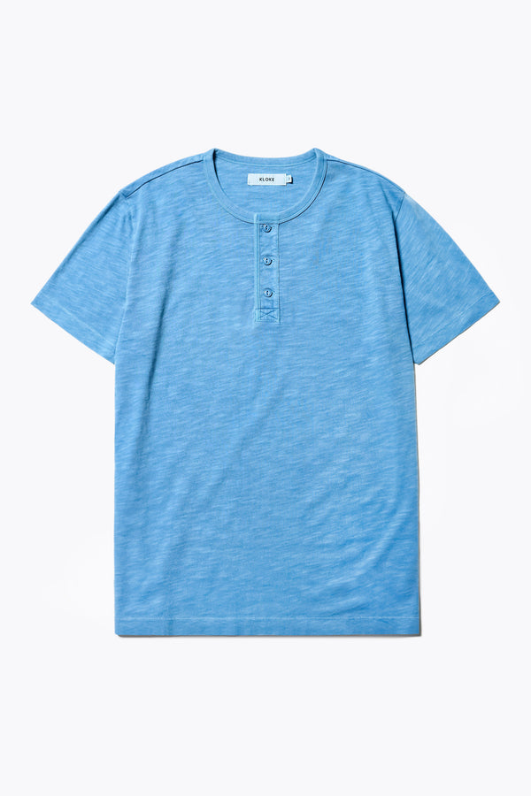 The Stratus Henley T-shirt in Blue. Garment-dyed in soft cotton jersey with three-button placket and coverstitched hems. Available in 5 sizes.