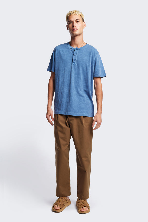The Stratus Henley T-shirt in Blue. Garment-dyed in soft cotton jersey with three-button placket and coverstitched hems. Available in 5 sizes.