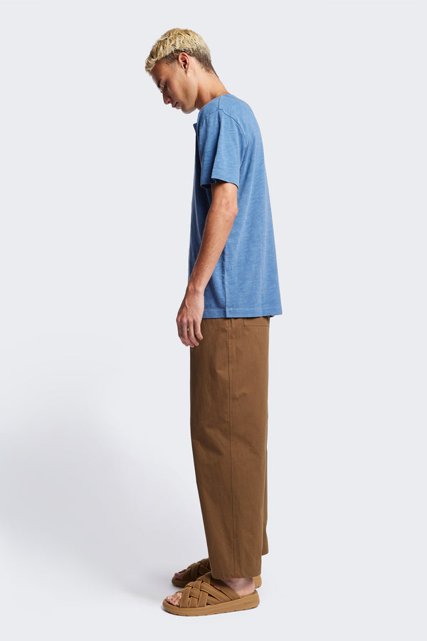 Side of The Stratus Henley T-shirt in Blue. Garment-dyed in soft cotton jersey with three-button placket and coverstitched hems. Available in 5 sizes.