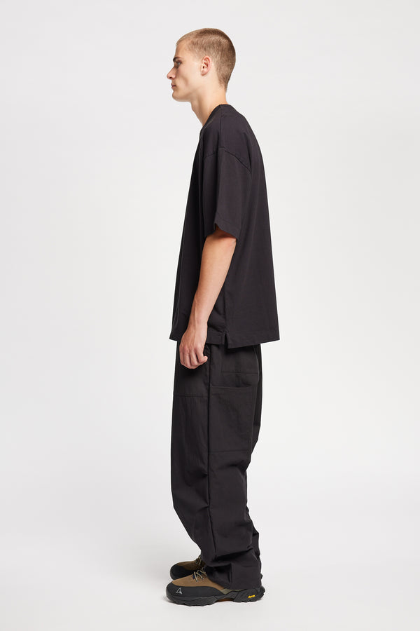 Men - side of model in Monolith Unisex Tee in Black. Oversized relaxed fit. Available in 6 sizes. Made form 100% Organic Cotton.