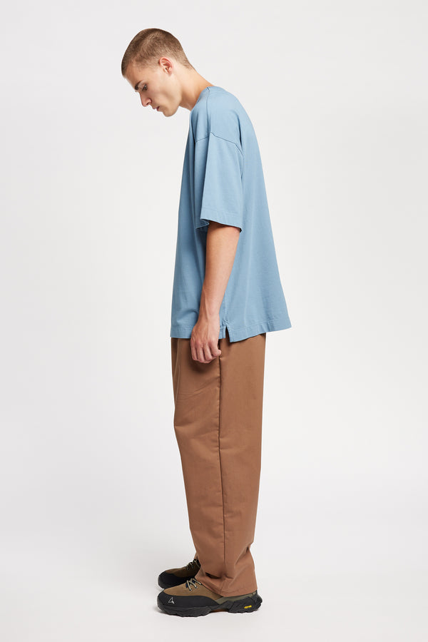 Men - side of model in Monolith Unisex Tee in Blue. Oversized relaxed fit. Available in 6 sizes. Made from 100% Organic Cotton