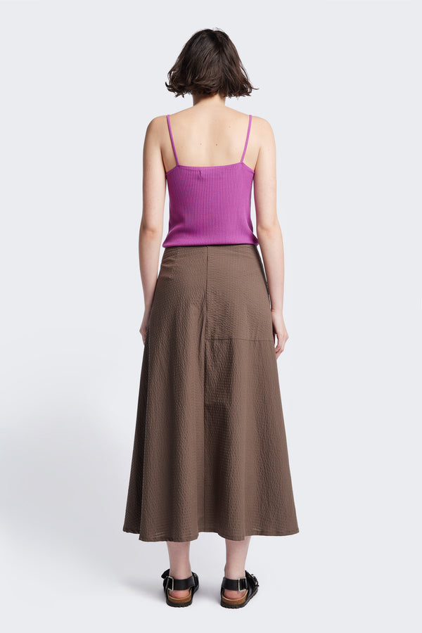 The back if the Abroad Panel Skirt, fitted at the waist with a bias-cut maxi silhouette, made from 100% cotton in Brown. Features panel details, side pockets, and an invisible back zip. Available in 6 sizes.