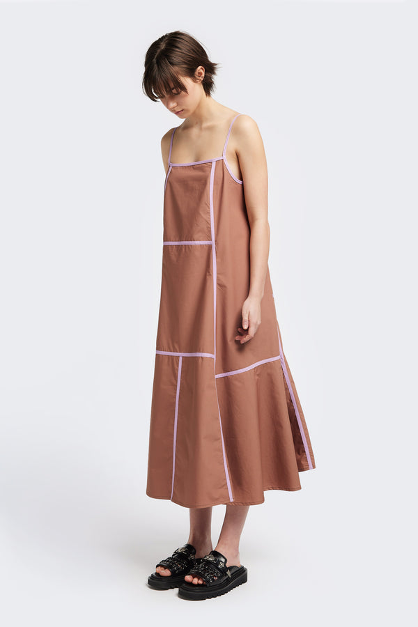 Front of the Adjourn Dress in brown/lilac, featuring contrasting block colours, bound seam details, adjustable thin straps, a straight neckline, and a flared A-line skirt. Available in 5 sizes.