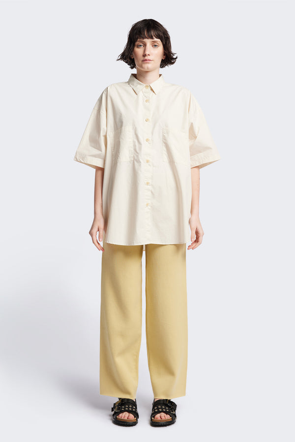 (women) Relaxed loose-fitting boxy short-sleeve shirt with back button placket, scoop hemline, and chest patch pockets, crafted in lightweight cotton poplin. Available in 5 sizes.
