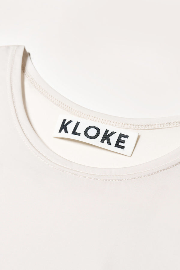 Close up fabric shot of off white Convoy short sleeve fitted top in recycled poly with slim silhouette and classic crew neckline