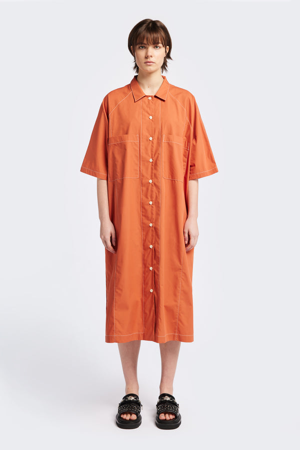 The Daily Dress Rust with white contrast topstitch is a button up dress with patch-pockets at the front, inseam side pockets and shirt collar. This oversized style is made from an all natural cotton.