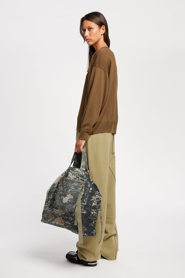 Side view on Model of the Descend Loose Fit Merino Knit in brown, a relaxed-fit merino wool sweater with a crew neck.