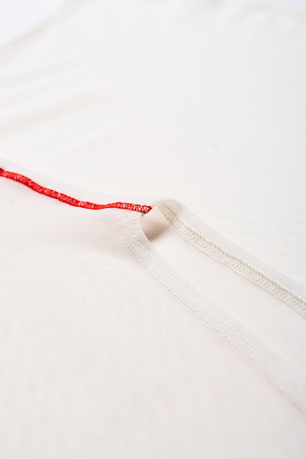 Close up details of the Flow Mesh Short Sleeve Top in Ecru and Red. Featuring a high neckline, contrast flatlock seams, and sheer, lightweight fabric, perfect for layering.