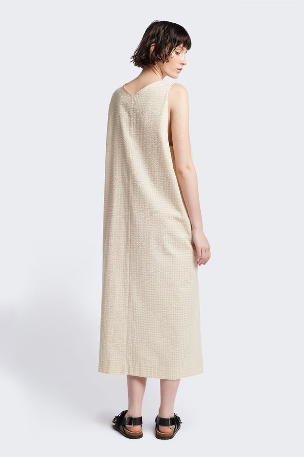 Back of the Long-length Forces Pinafore Dress in Ecru Beige Kloke designed soft seersucker premium cotton . Relaxed fit with a deep rounded neckline, front patch pockets, and a front split for ease of movement. Available in 5 sizes.
