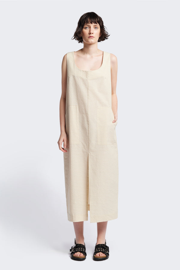 Long-length Forces Pinafore Dress in Ecru Beige Kloke designed soft seersucker premium cotton . Relaxed fit with a deep rounded neckline, front patch pockets, and a front split for ease of movement. Available in 5 sizes.